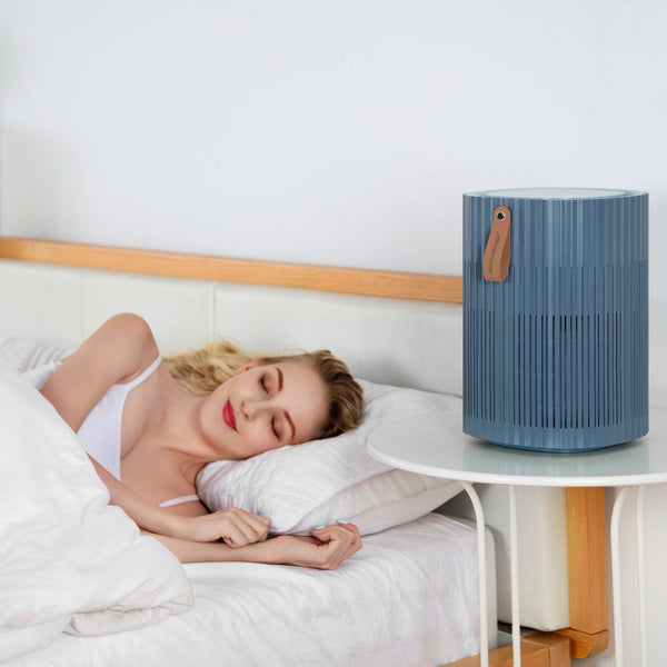 Dame slapend in bed met AirExchange 150‑T, fluisterstille luchtreiniger voor in de slaapkamer, voor schone lucht en betere slaap, blauw