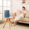 Dame in woonkamer met AirExchange 150‑T, fluisterstille luchtreiniger, voor schone lucht en betere slaap, blauw